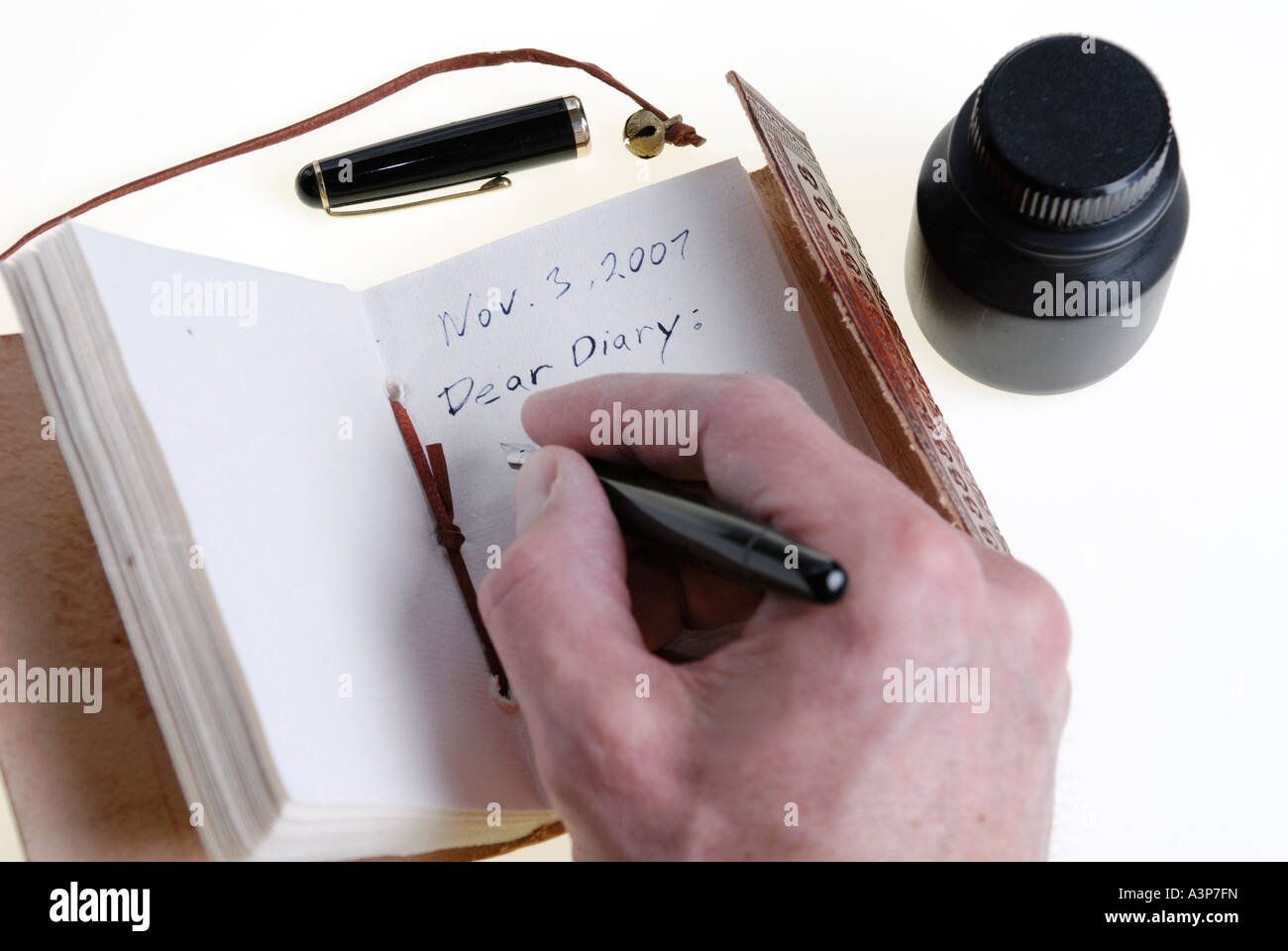 L'écriture dans un journal en cuir avec stylo plume et encre bouteille Banque D'Images