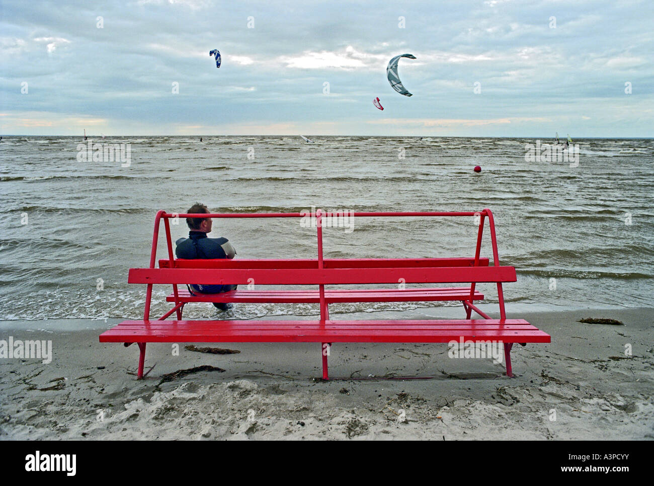 L'homme sur un banc de la plage à la baie de Parnu, Estonie Banque D'Images