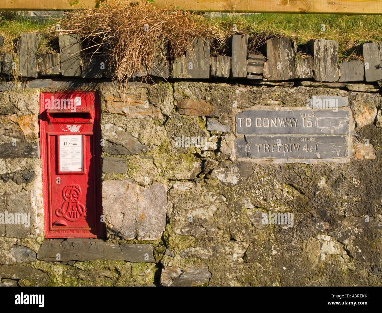 George VII post box rouge ardoise gravée panneaux indicateurs dans mur de pierre Betws-Y-Coed Conwy North Wales UK Banque D'Images