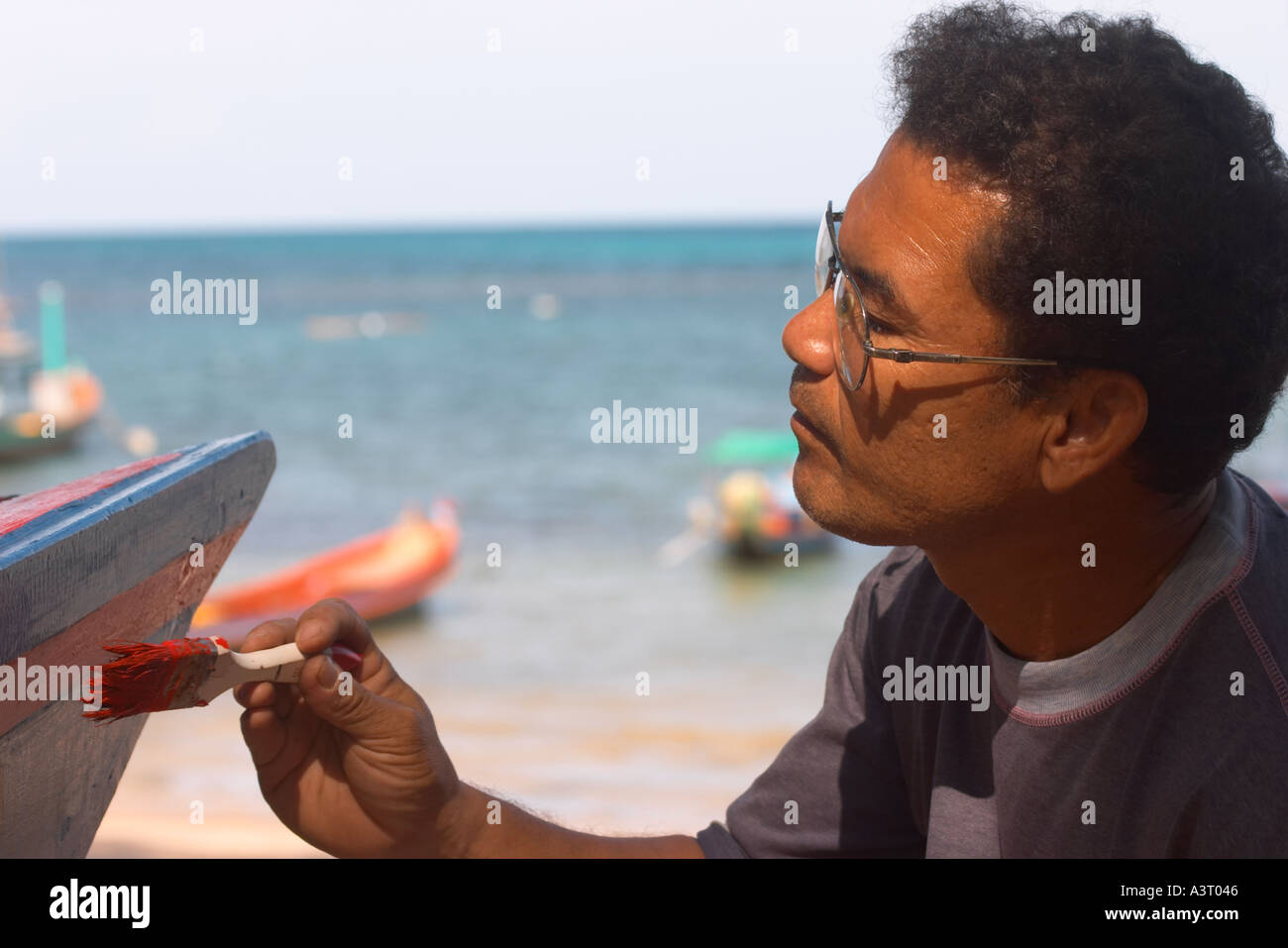 Man On a Beach Peinture d'un bateau en Thaïlande Banque D'Images