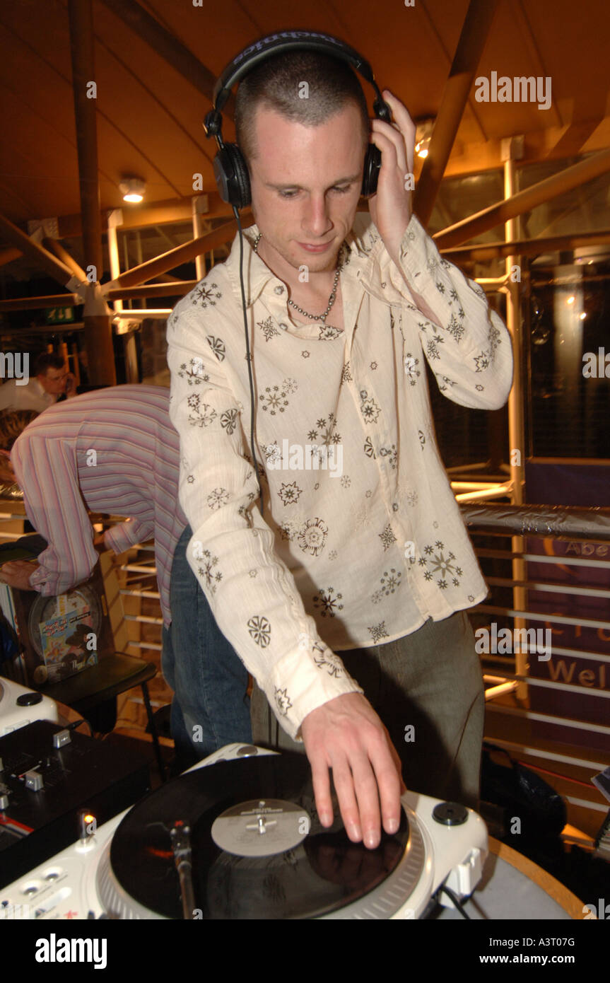 Disc Jockey DJ portant des écouteurs queuing 12 inch vinyl record sur la plaque de l'Université d'Aberystwyth Ball Mai 2005 Banque D'Images