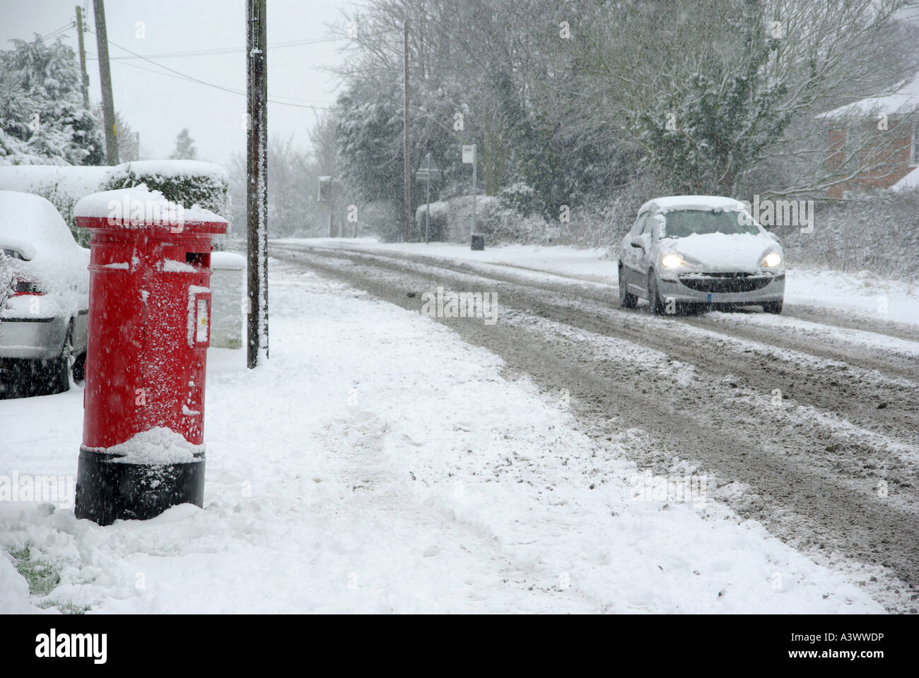 Route de campagne avec la neige qui tombe pour les conducteurs de voitures avec phares sur comprend fort du pilier rouge Banque D'Images