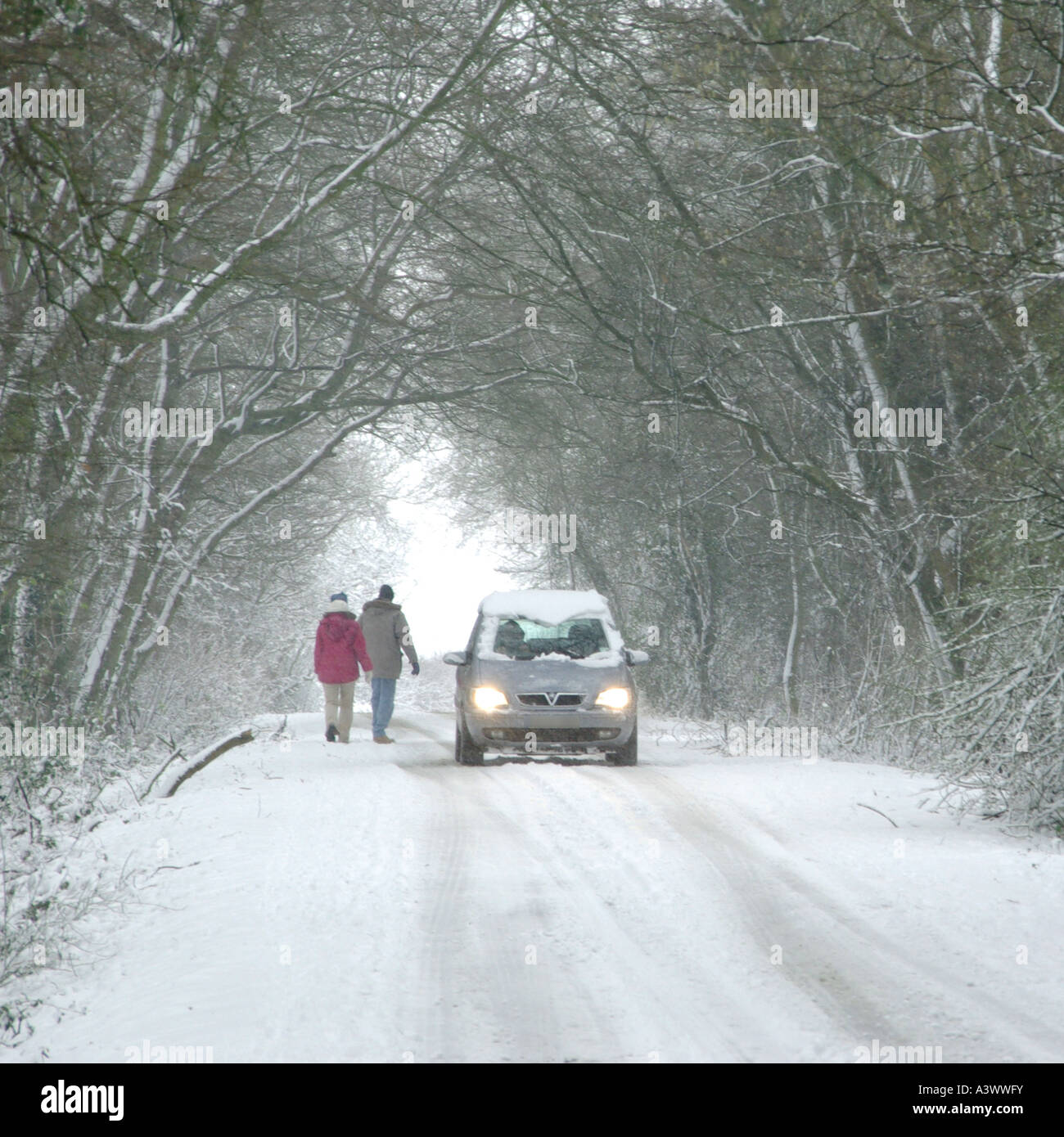 Les gens qui marchent en pays voie pendant plus de déménagement de neige pour permettre de passer de voiture de route allumés Banque D'Images