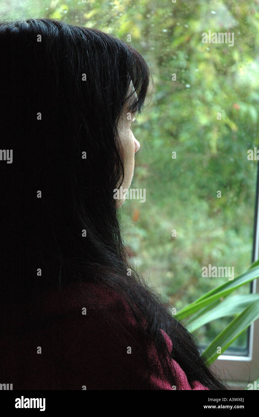 Woman staring out d'une fenêtre en hiver pluie éclaboussé Banque D'Images