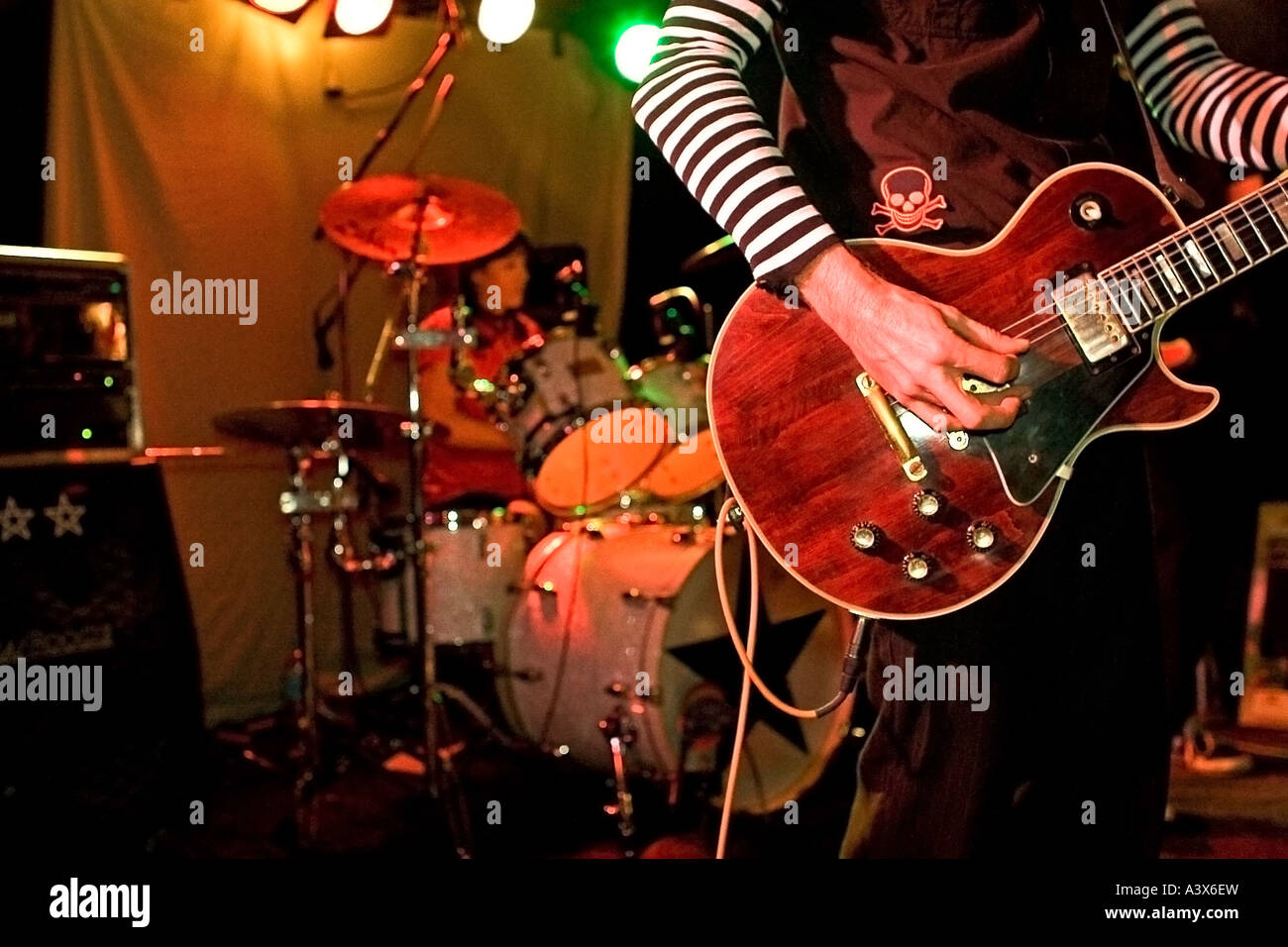 Close Up Rock and Roll guitariste sur scène avec le batteur dans l'arrière-plan. Banque D'Images