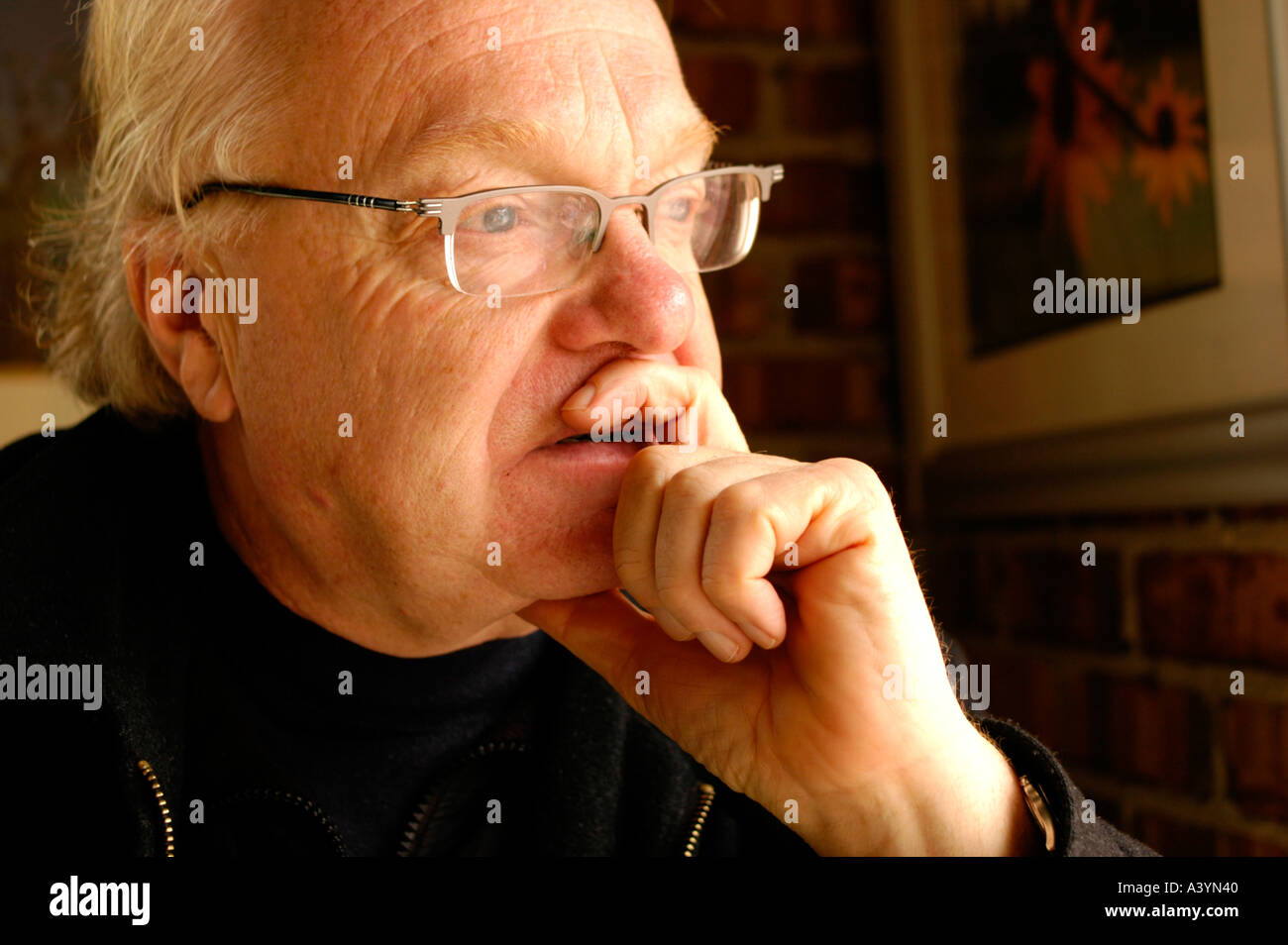 Homme plus âgé avec des lunettes à la recherche d'une fenêtre et la pensée Banque D'Images