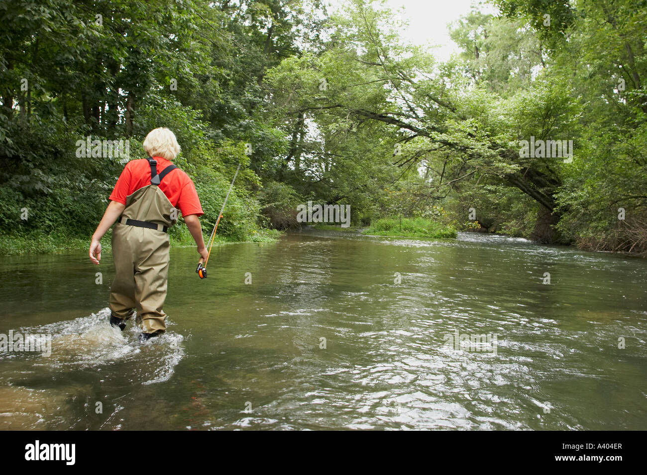 Garçon marchant à travers un ruisseau flyfishing Banque D'Images