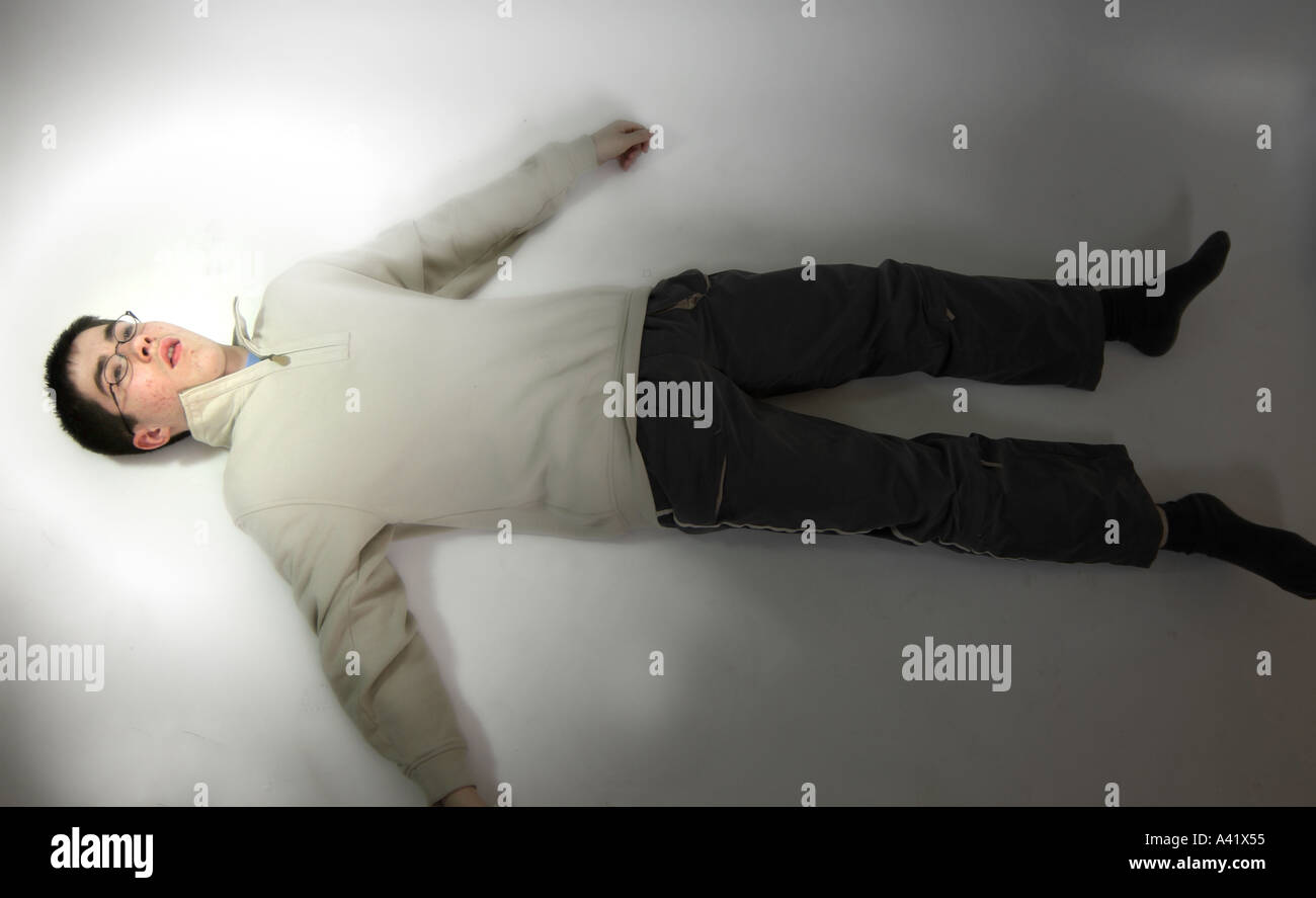 Jeune garçon se couche sur le plancher comateux Banque D'Images