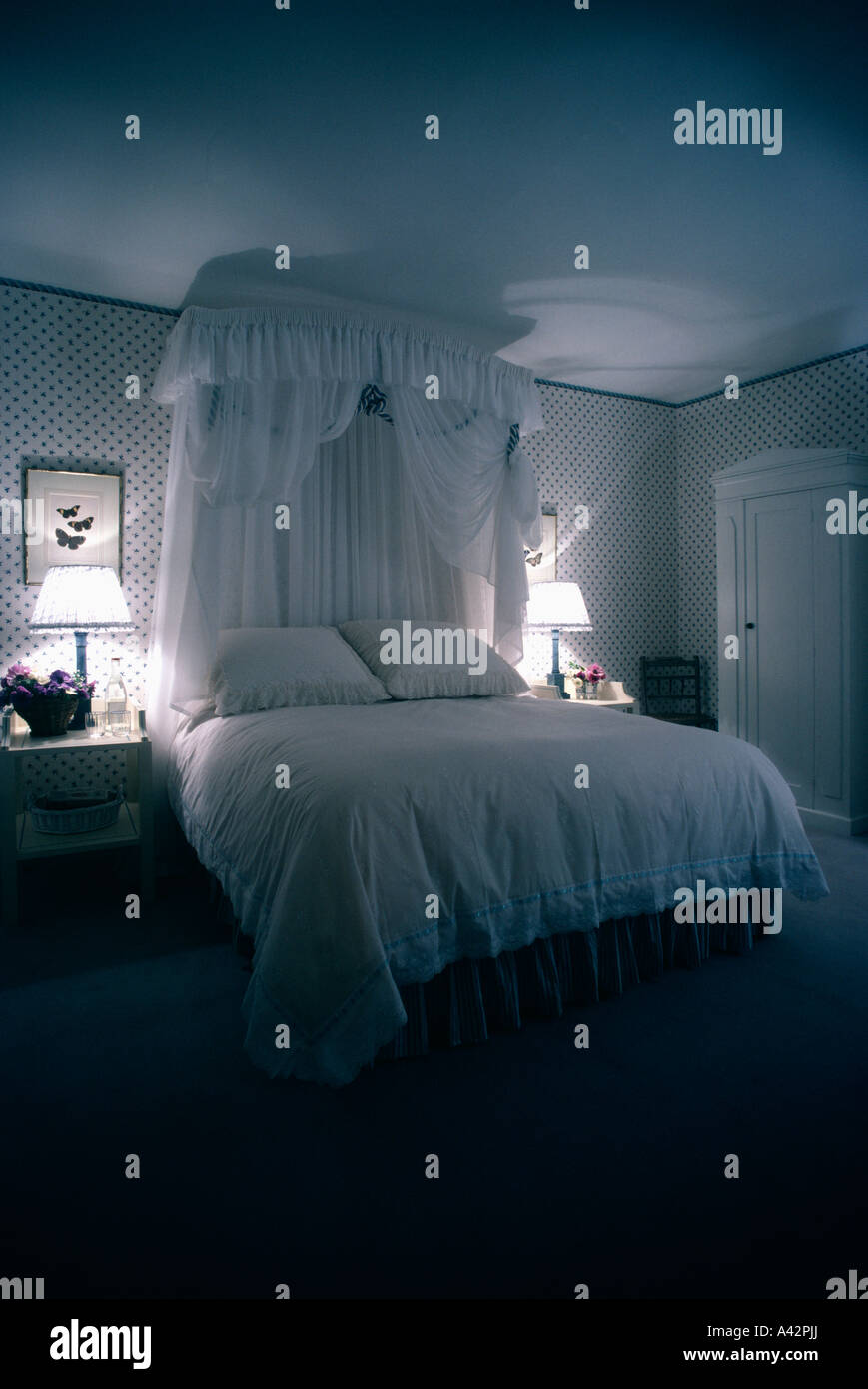 Lit à dais avec rideaux de dentelle et couvre-lit dans chambre à coucher  romantique avec des lampes allumées Photo Stock - Alamy