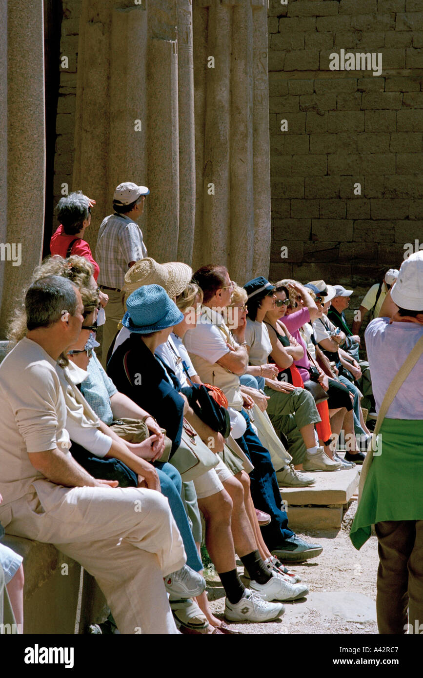 Les touristes se reposer pendant l'écoute de leur guide dans le temple de Louxor en Égypte Banque D'Images