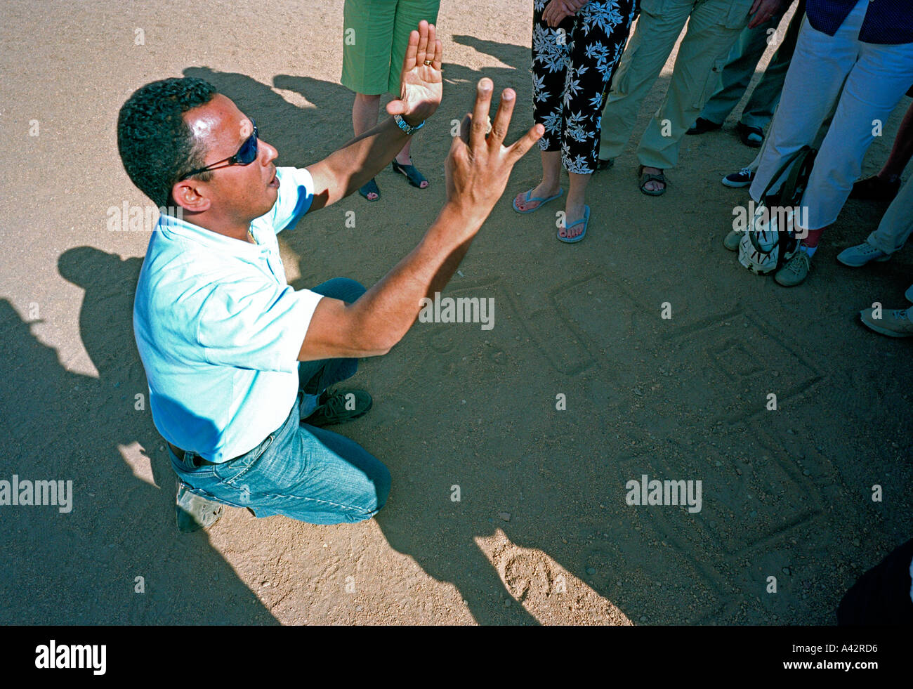 Un guide touristique illustre graphiquement l'architecture des temples dans la poussière au temple d'Horus à Edfou Banque D'Images