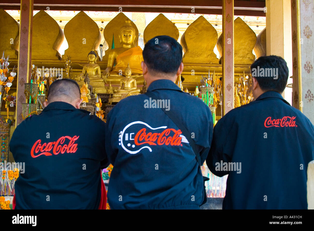 Coca Cola employés priant Wat That Luang Vientiane Laos Banque D'Images