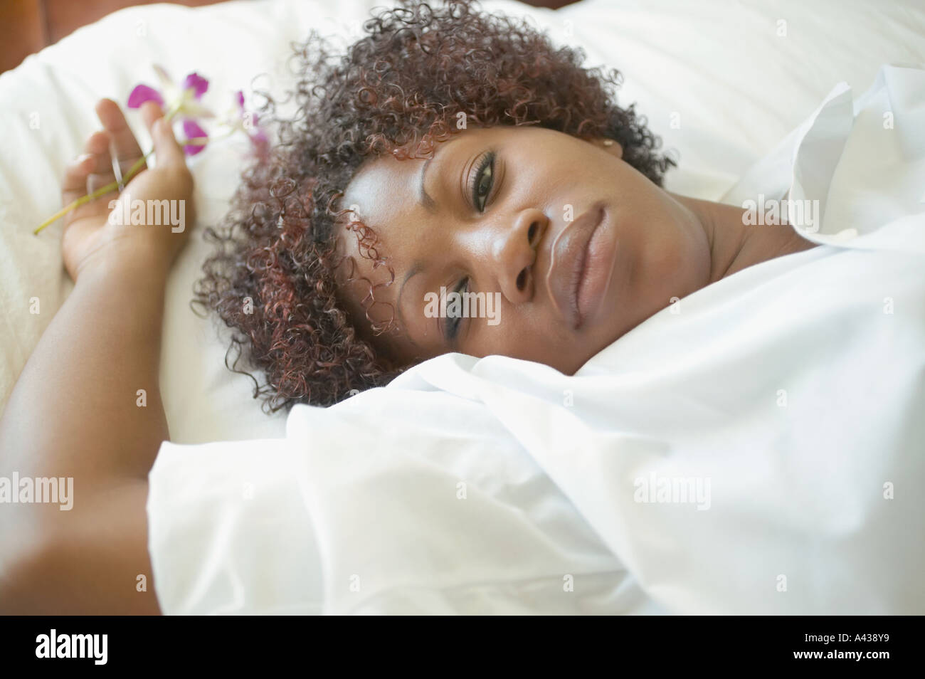 Portrait of woman laying on bed holding Flowers Banque D'Images