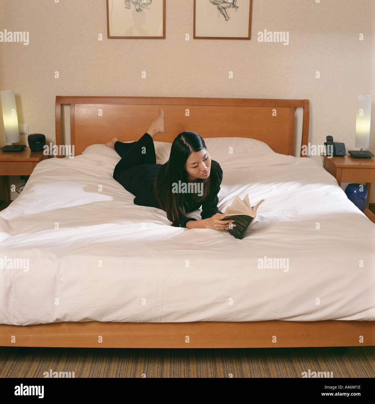 Woman reading on bed Banque D'Images