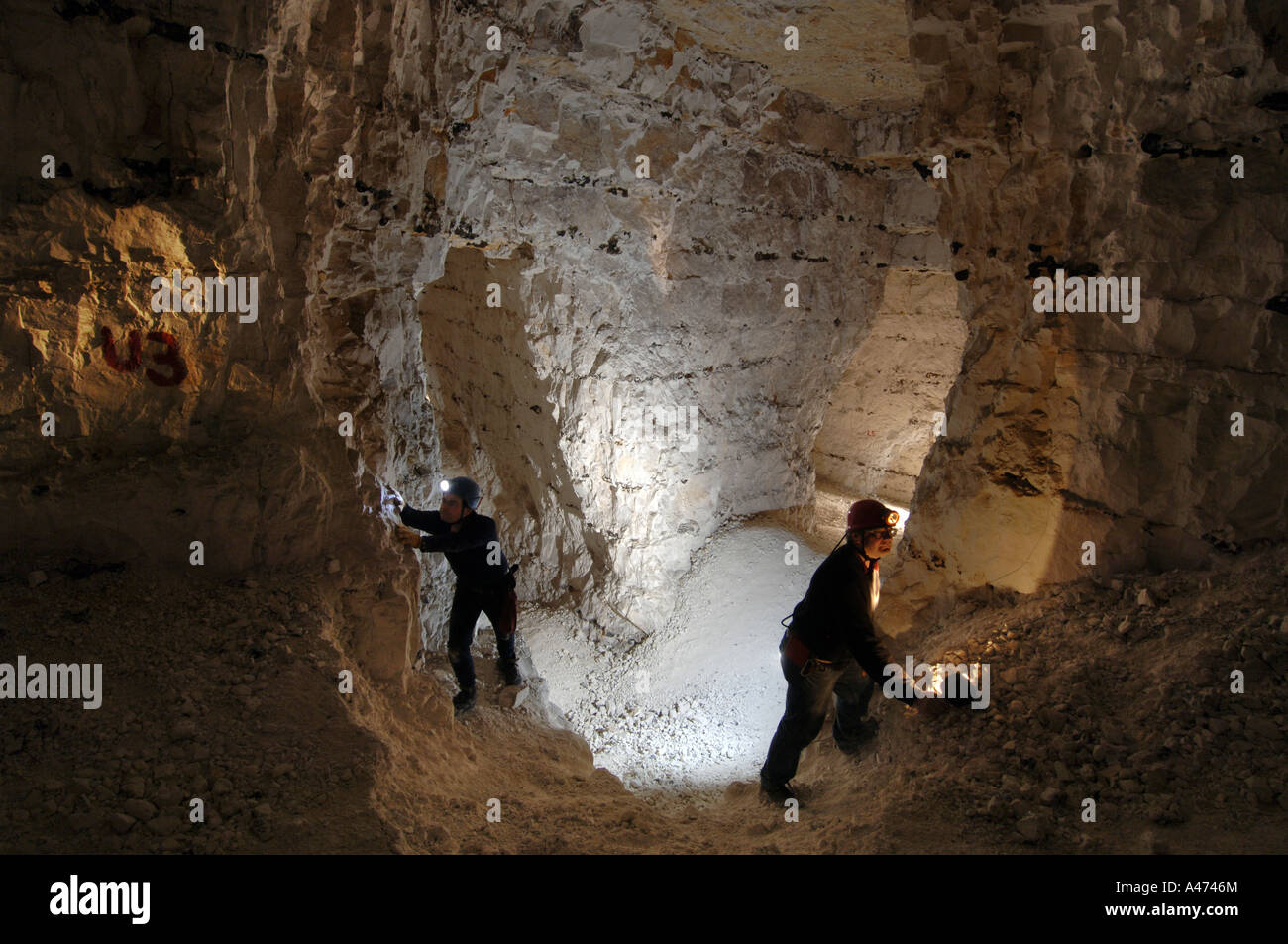 Deux spéléos explorer une chambre souterraine, dans une ancienne mine de craie ci-dessous qui lit Banque D'Images