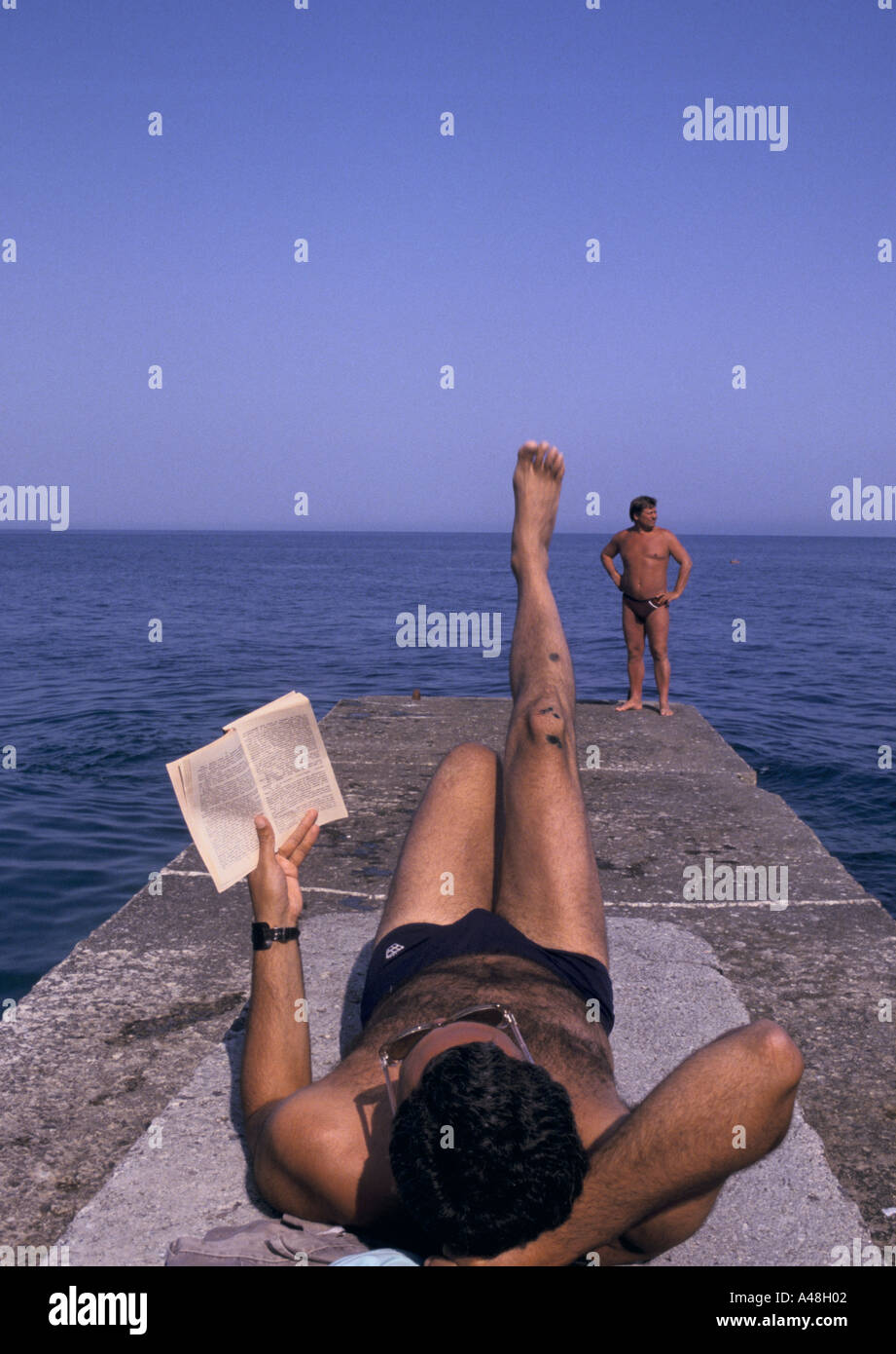 A Man reading et bronzer au bord de la mer de la mer Noire à Yalta Banque D'Images