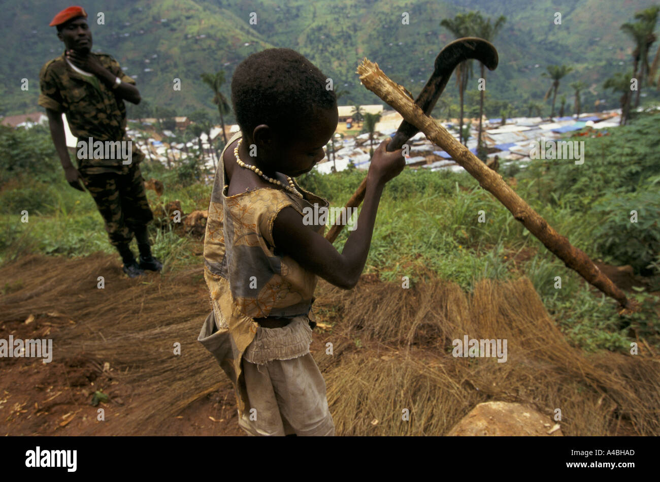 Bohonga camp de regroupement, le Burundi Feb 2000 : un soldat garde le camp regarde une jeune fille coupe de bois de chauffage Banque D'Images