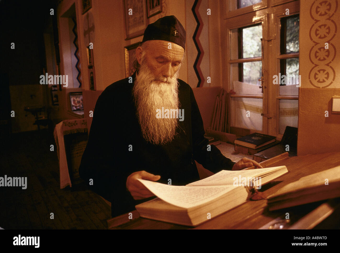 Tronosa monastère, la Serbie. Un moine orthodoxe serbe avec longue barbe grise lit un gros livre Tronosa au monastère. Banque D'Images