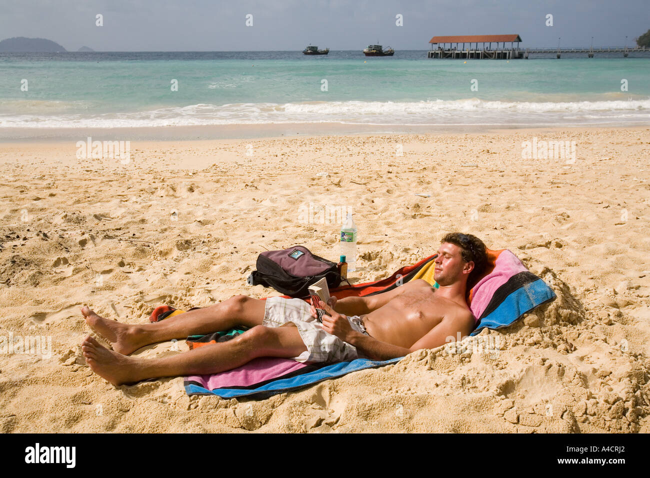 La Malaisie Pulao Tioman beach village Salang soleil man reading Banque D'Images