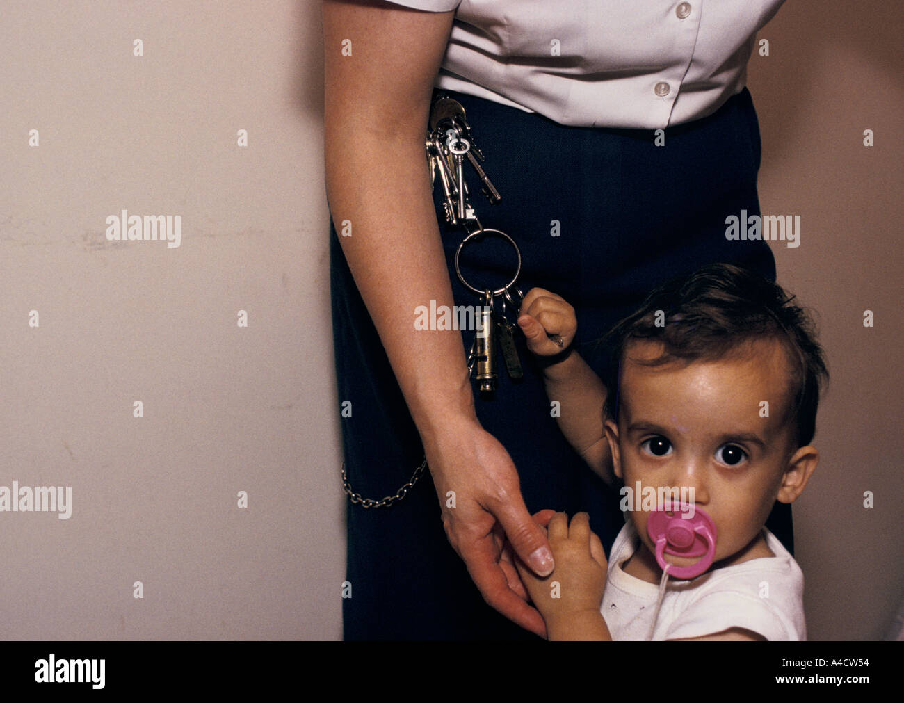 Le bébé d'un prisonnier joue avec les touches d'un gardien de prison. Banque D'Images