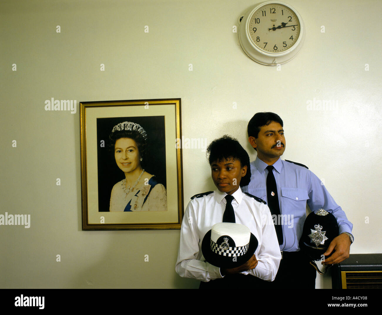 Les agents de police asiatique debout à côté d'un portrait de la reine Banque D'Images