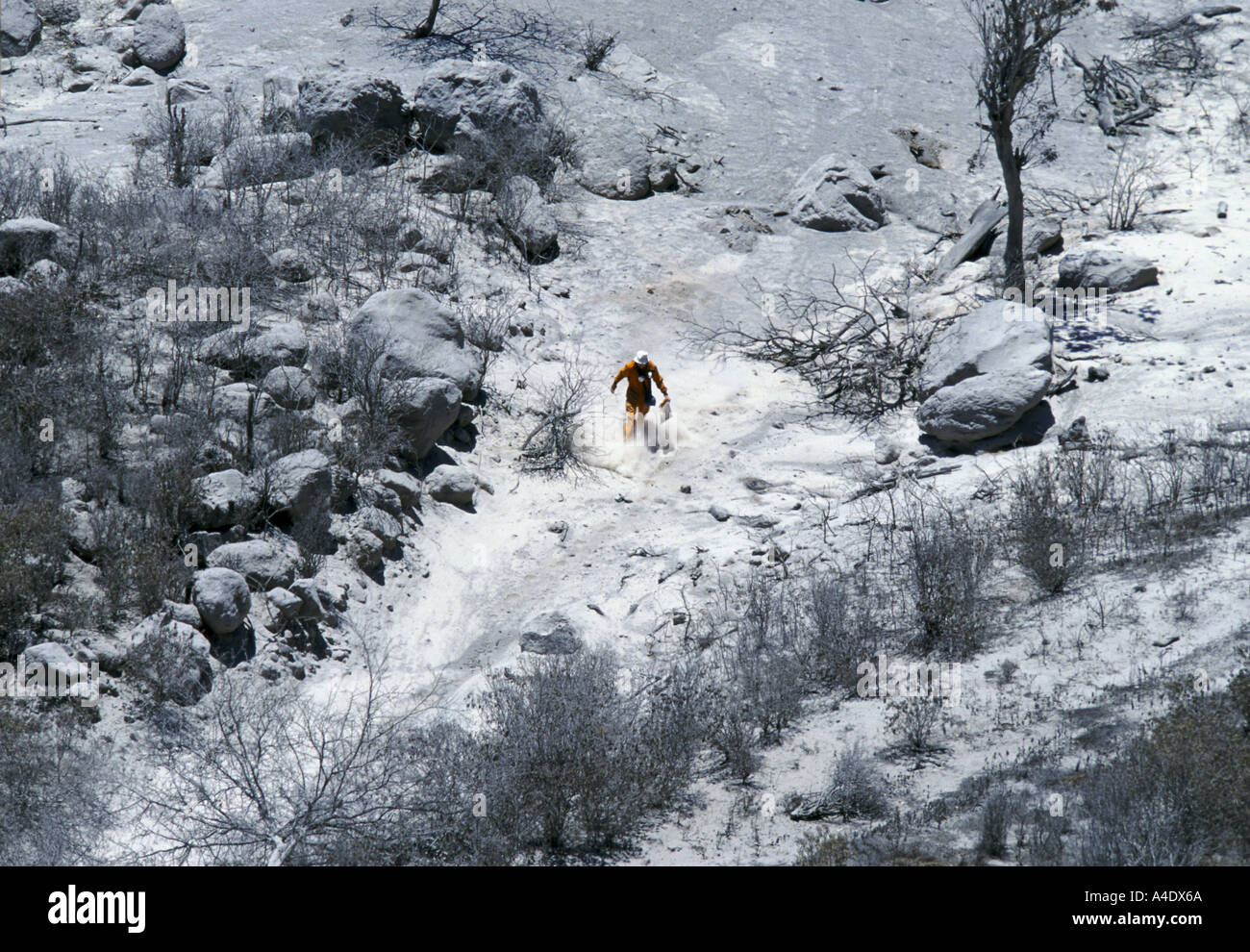 Expert scientifique en portant un costume de chaudière orange marche dans une colline couverte par les cendres de l'éruption du volcan de Montserrat Banque D'Images