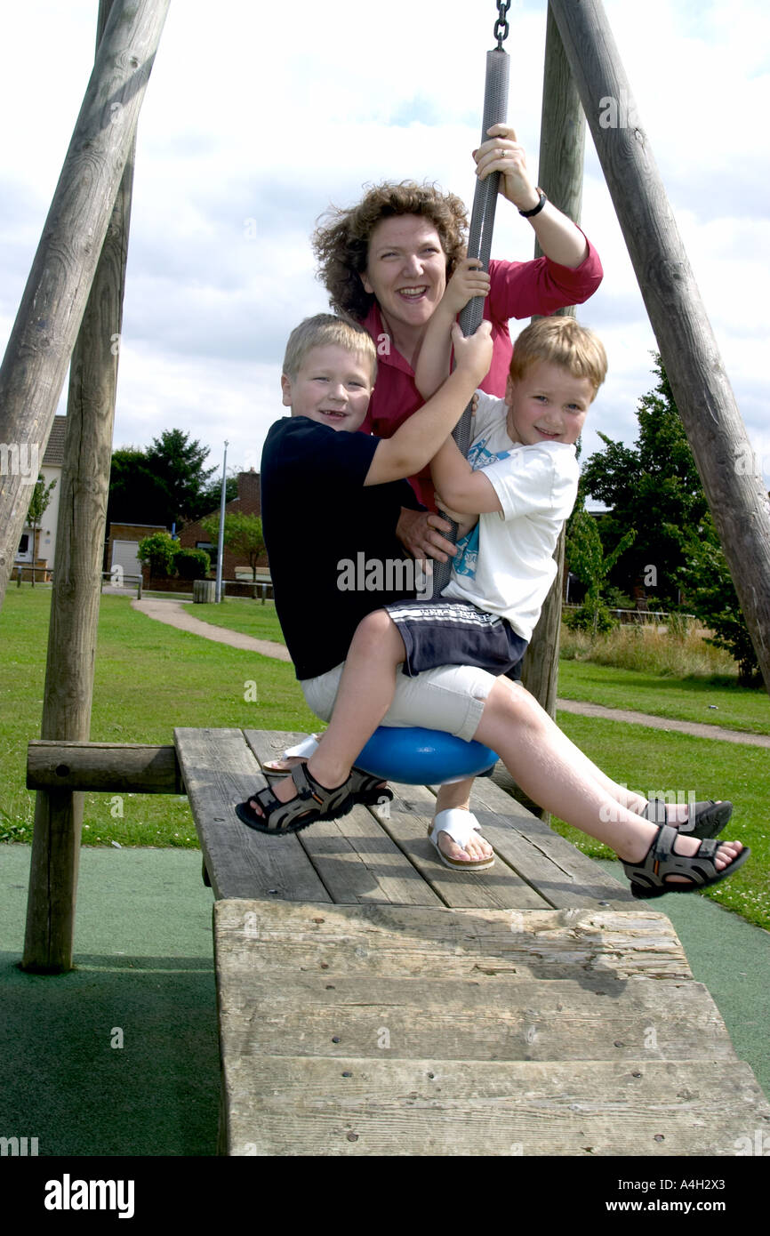 Une mère jouant avec ses deux enfants sur une balançoire. Banque D'Images