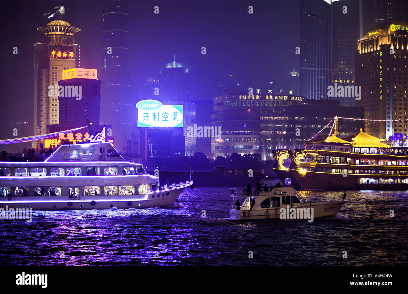Chine SHANGHAI illuminée brillamment les bateaux d'excursion et de bateaux dragons en passant par la ligne d'horizon du nouveau quartier financier de Pudong Banque D'Images