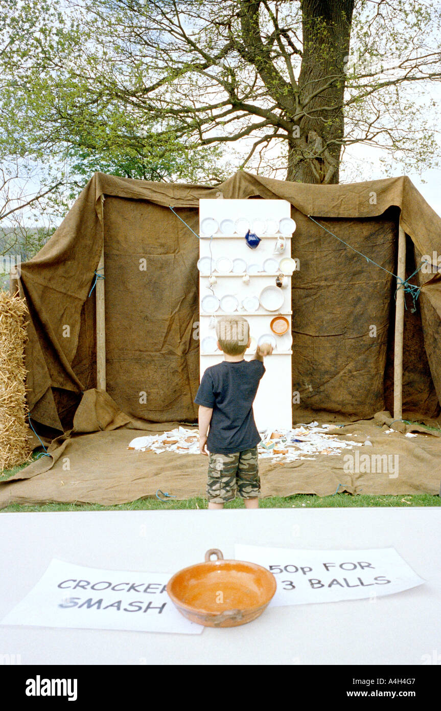 Un garçon jouant un jeu à un écrasement de la vaisselle country fair. Banque D'Images
