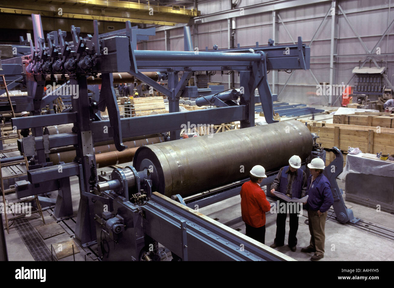Trois hommes ont examiné le document dans une usine de papier Banque D'Images
