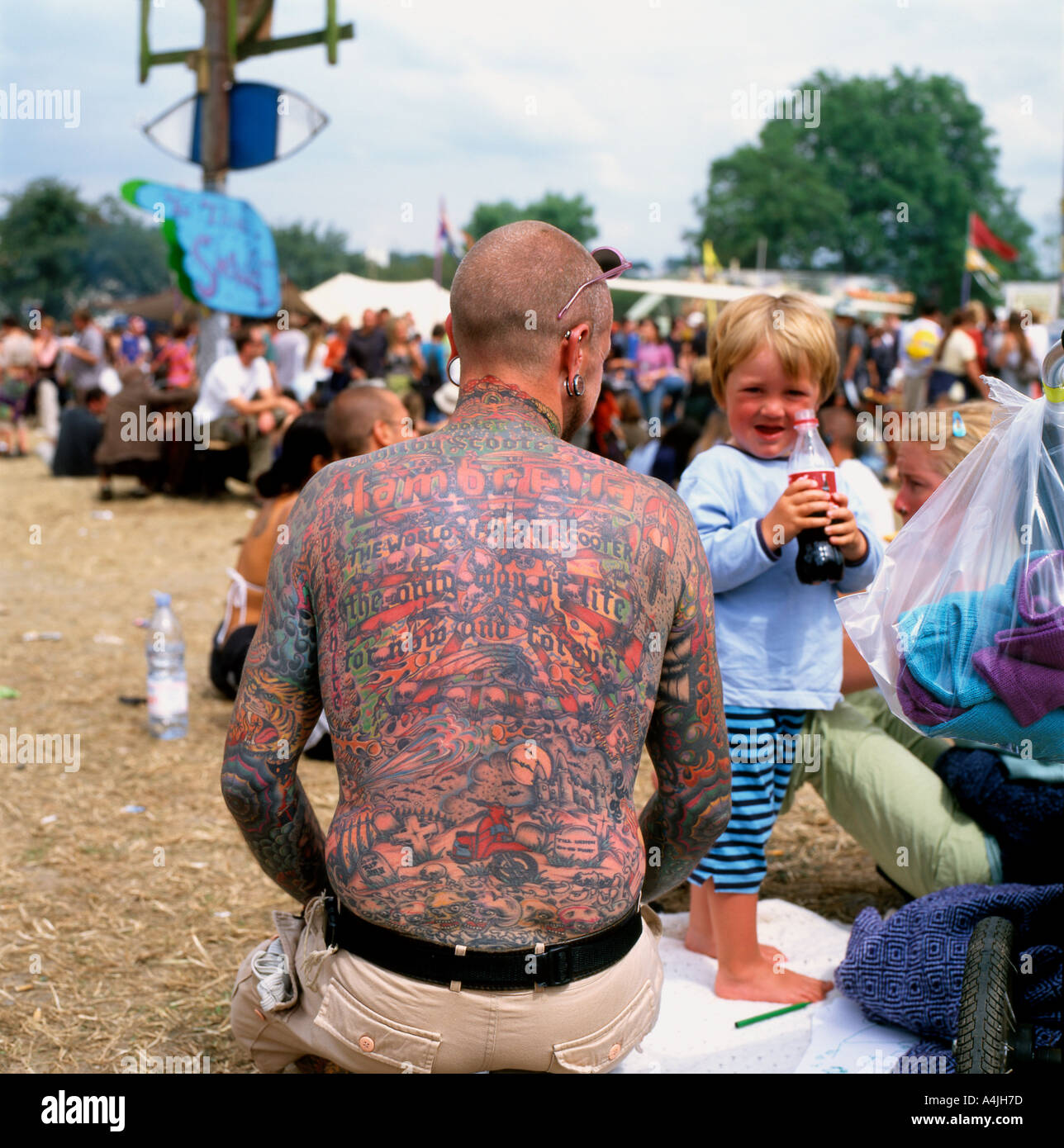 Homme père avec tatouages sur le dos et petit enfant tenant un verre au Glastonbury Festival Somerset en Angleterre KATHY DEWITT Banque D'Images Homme père avec tatouages sur le dos et petit enfant tenant un verre au Glastonbury Festival Somerset en Angleterre KATHY DEWITT Banque D'Images