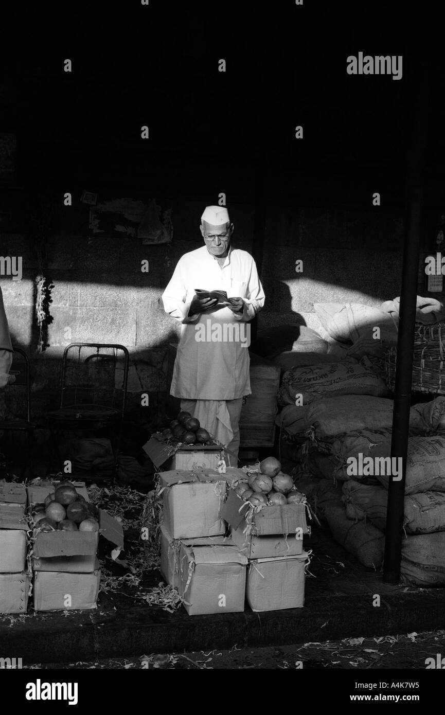 Un vieux vendeur de fruits se lit le journal du matin au marché Crawford à Bombay ou Mumbai en Inde Banque D'Images