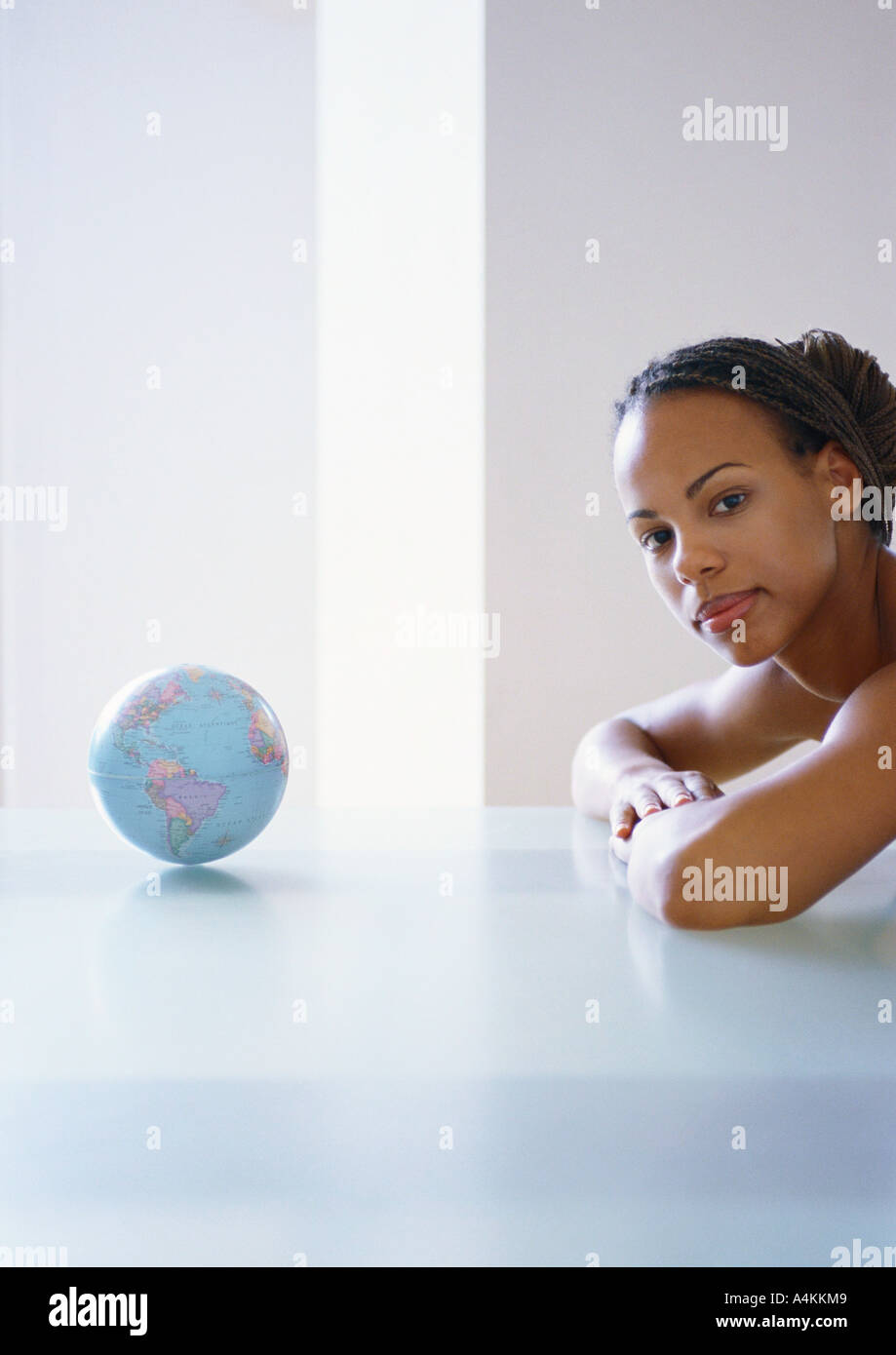 Femme avec les bras sur la table à côté de la petite planète, à l'aide du tableau Banque D'Images
