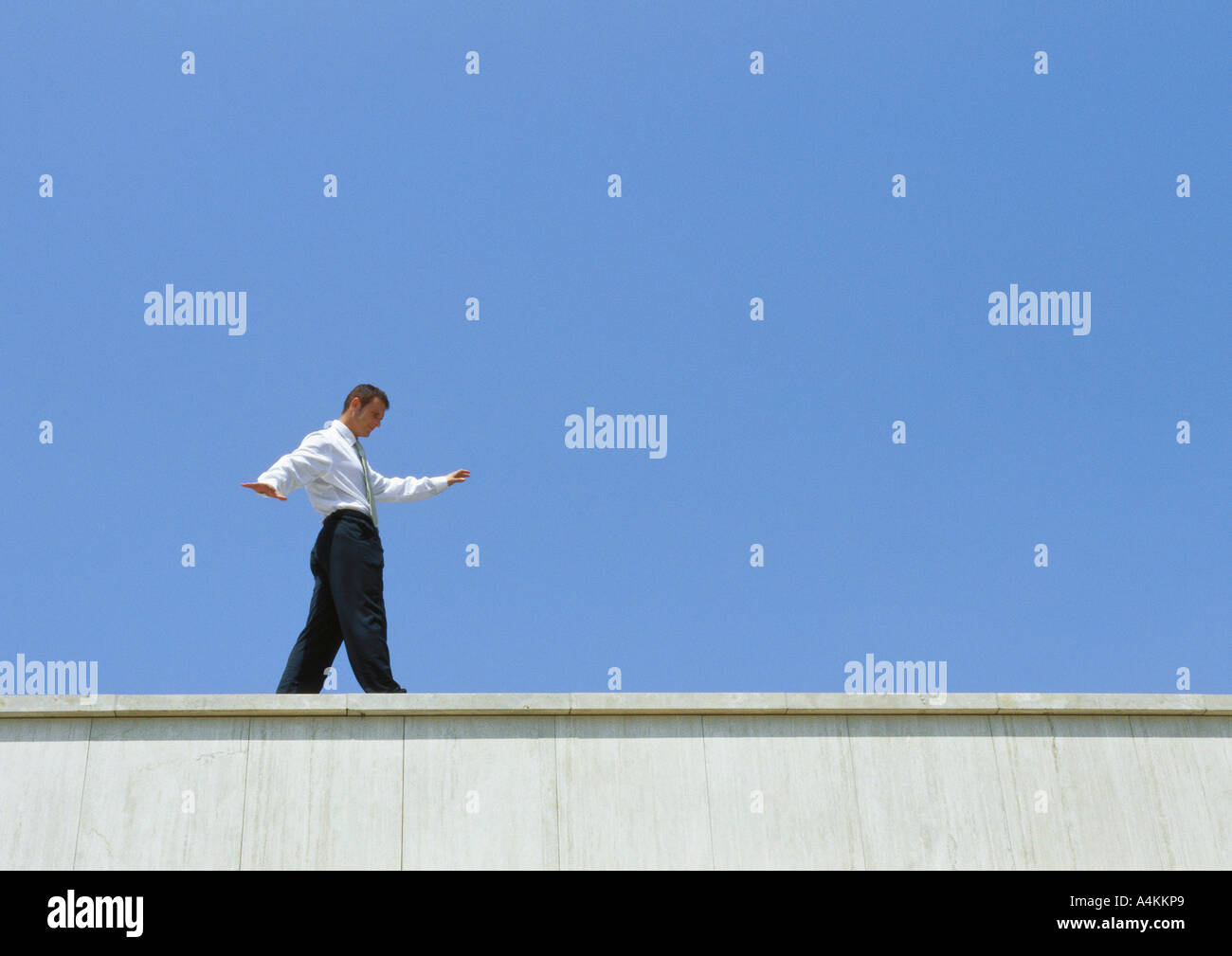 Businessman walking on edge of building, low angle view Banque D'Images