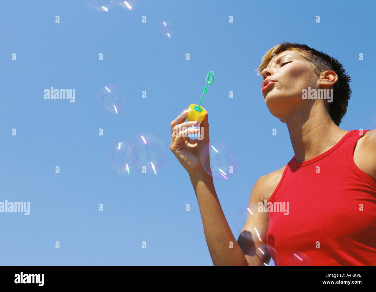 Woman blowing bubbles, low angle view Banque D'Images