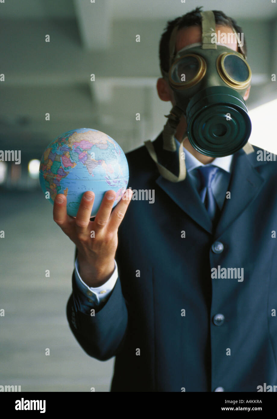 Businessman holding globe jusqu'à la main, portant un masque à gaz sur le visage Banque D'Images