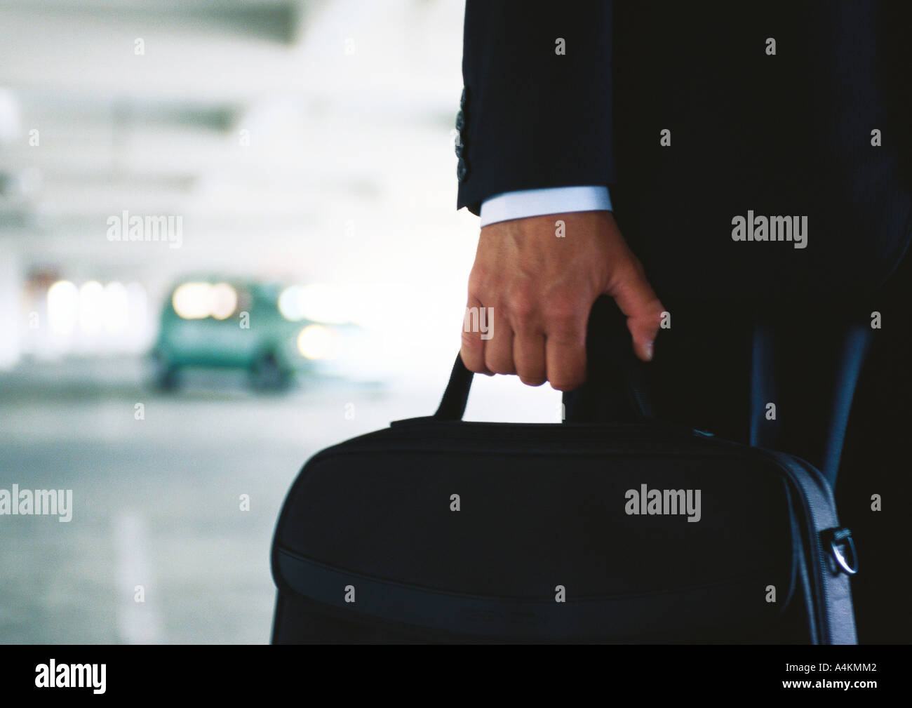 Businessman holding briefcase in parking garage, brouillées, close-up Banque D'Images