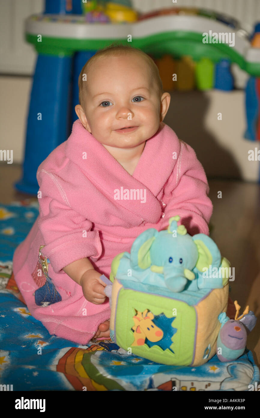 Sourire Mignon Bebe De 7 Mois Fille Assise En Robe De Chambre Rose Avec Doudou Cube Sur Une Couverture A La Maison Photo Stock Alamy