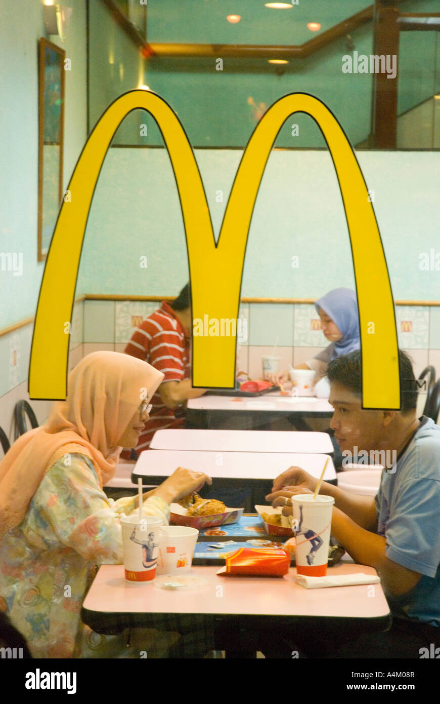 Un couple musulman prendre un hamburger dans un restaurant McDonalds halal à Kuching Sarawak Banque D'Images