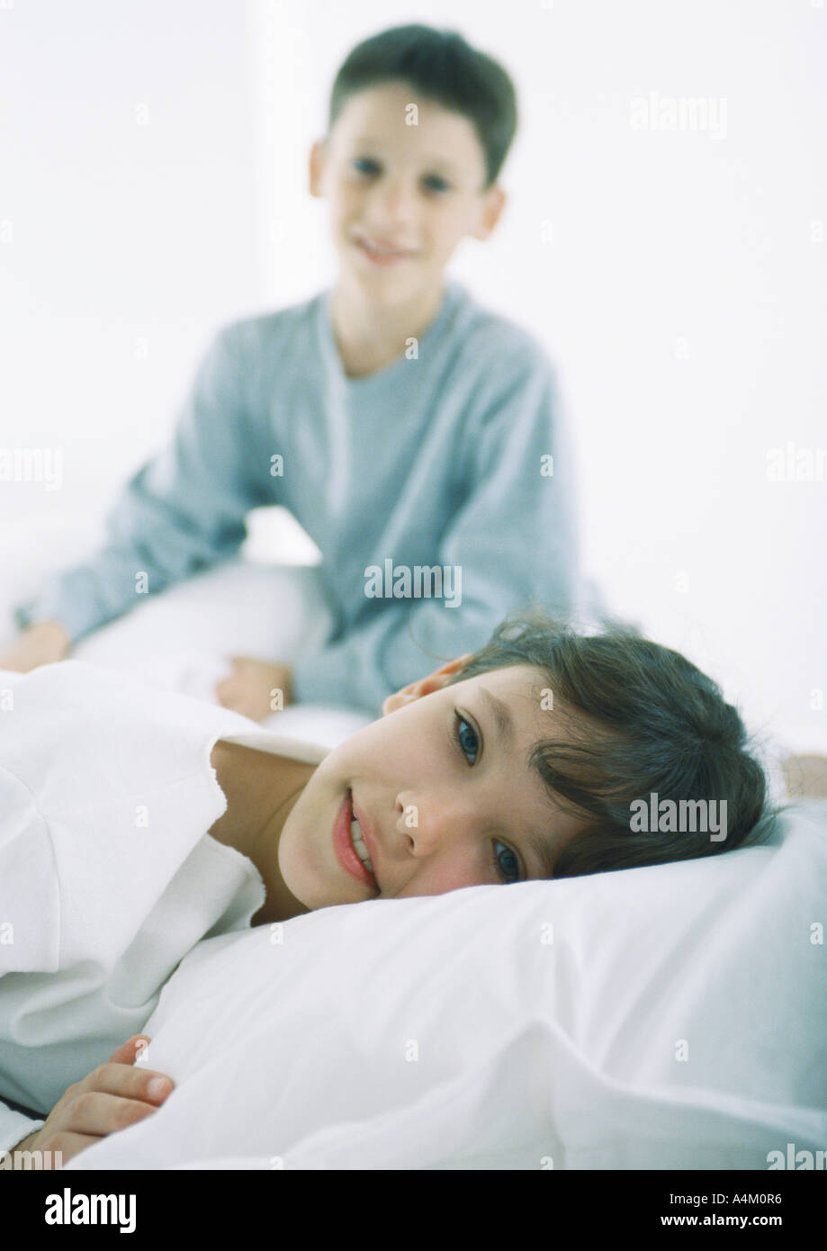 Girl Lying in Bed looking at camera, garçon en arrière-plan Banque D'Images