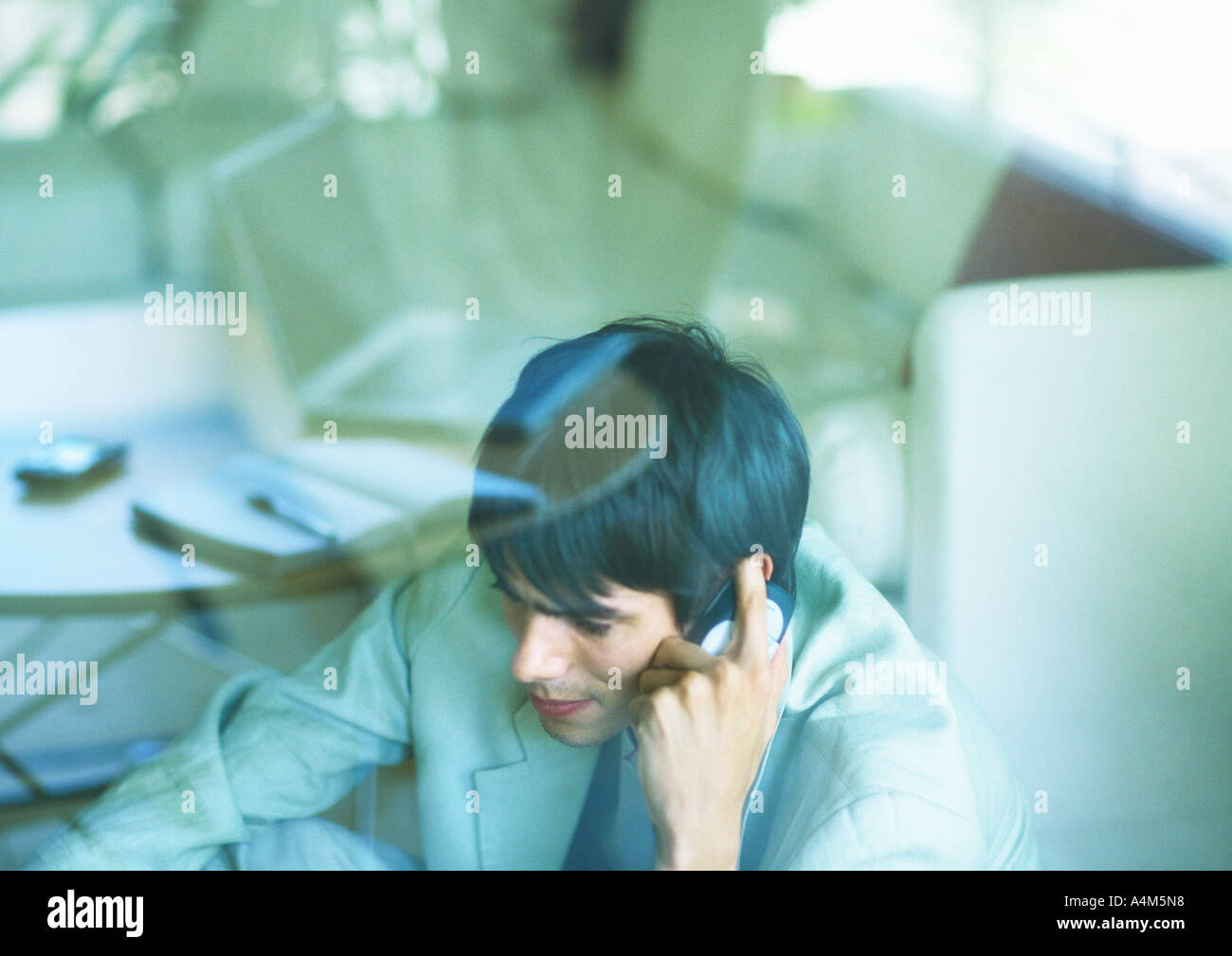 Man using cell phone, vu à travers vitre Banque D'Images