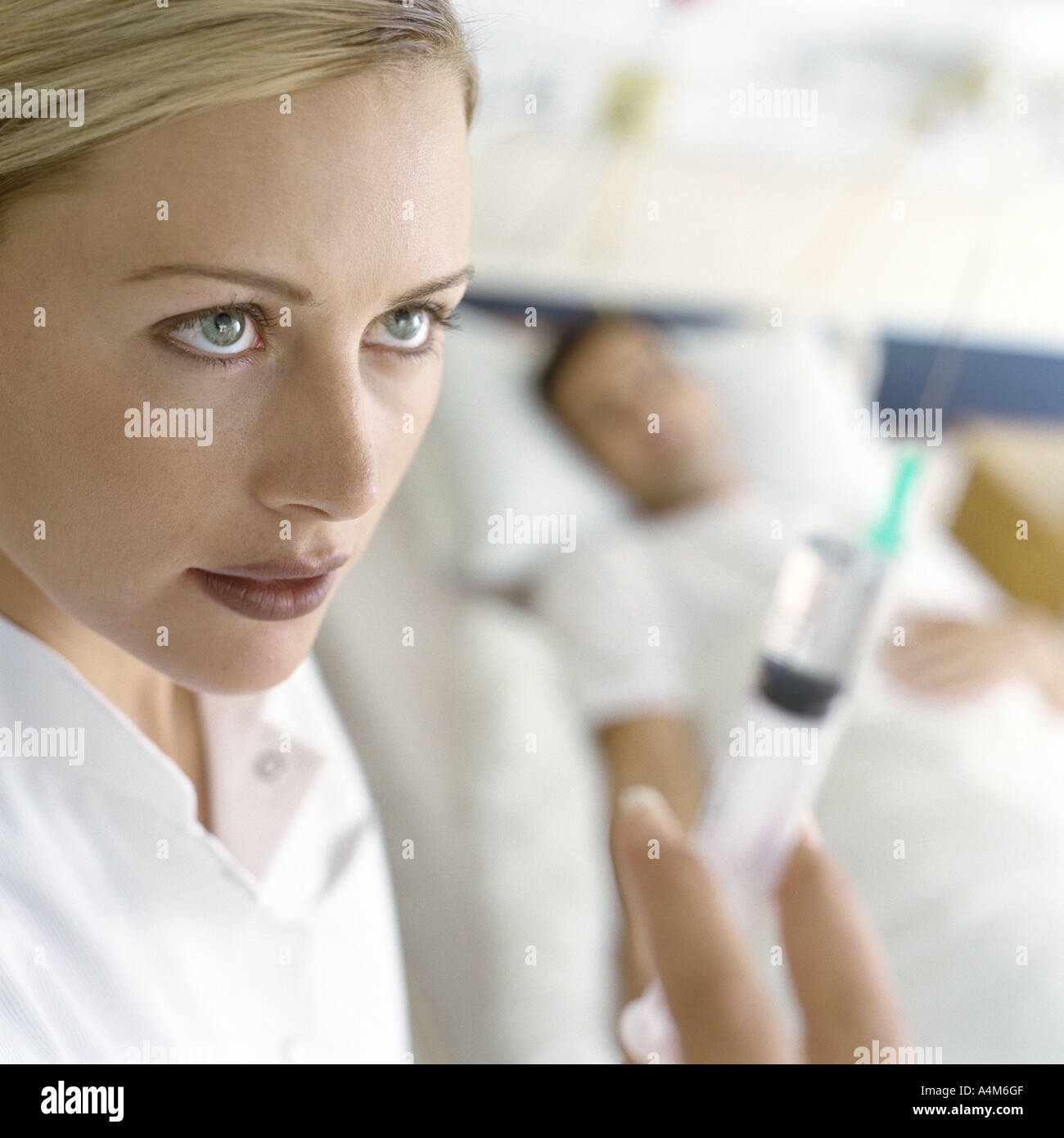 Nurse holding up syringe in front of patient Banque D'Images