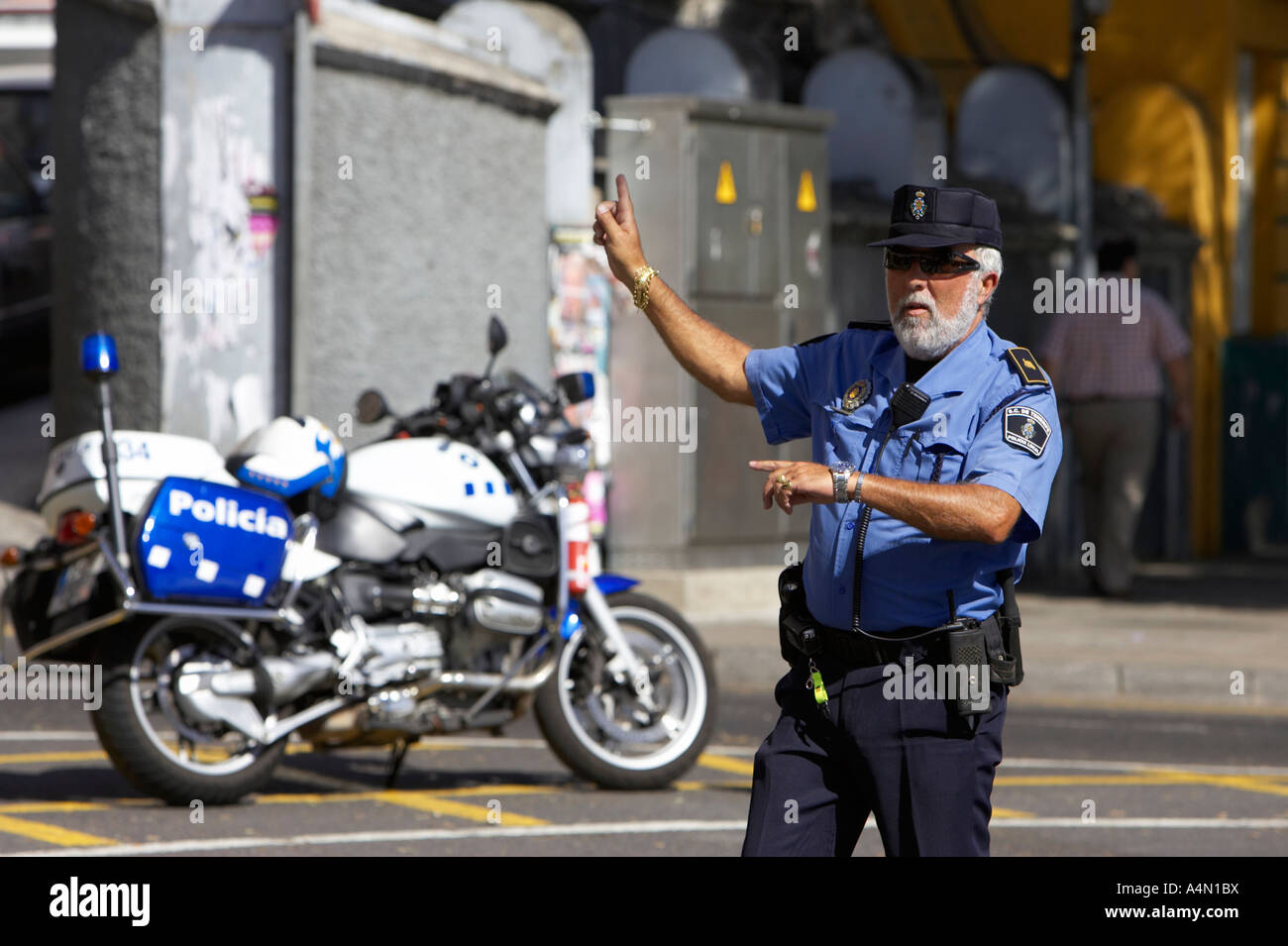 L'espagnol policia agent de la police locale sur les droits de trafic avec le vélo garé sur le côté de la route faisant des signaux à main Banque D'Images