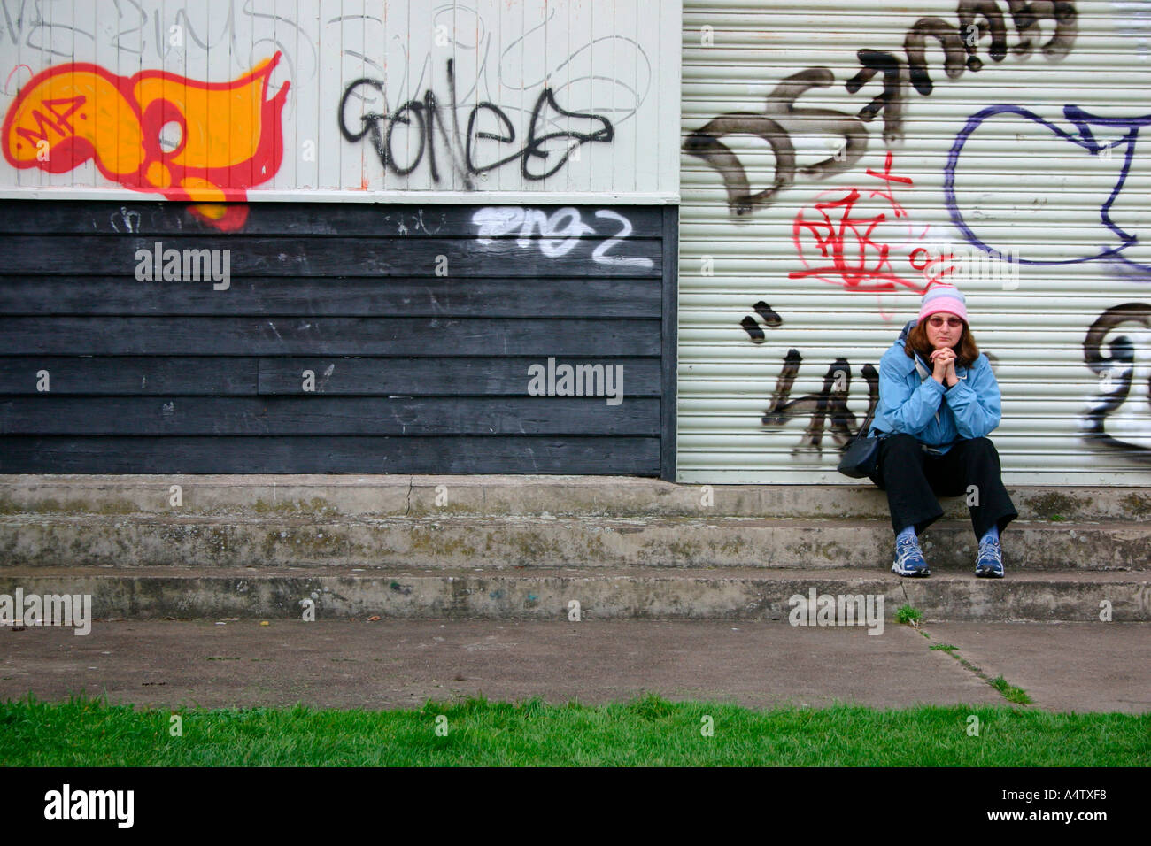 Femme assise en face de graffitis urbains, Cambridge, Angleterre. Banque D'Images