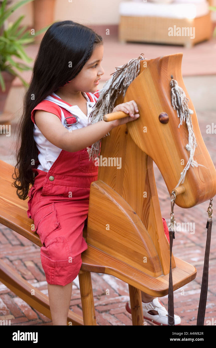 Jeune fille jouant sur cheval à bascule en bois Banque D'Images