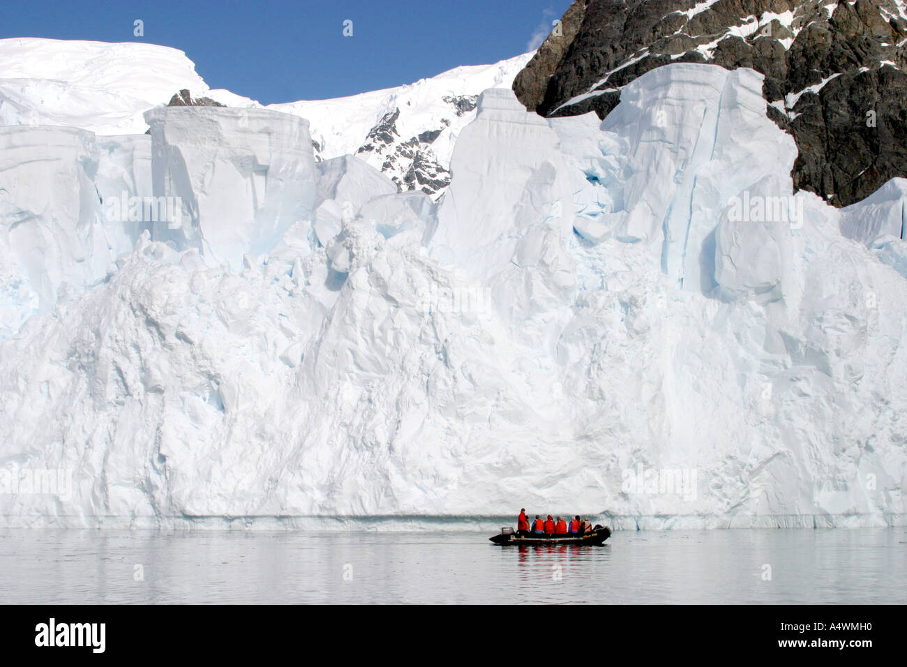 Groupe de voyageurs de l'Antarctique sur un canot zodiac croisière autour de hautes falaises de glace Banque D'Images