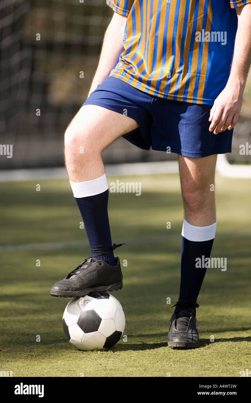 Soccer player holding ball avec son pied Banque D'Images