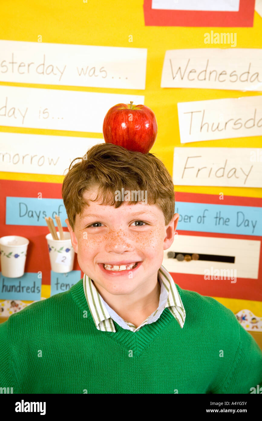 Garçon avec apple on head in classroom Banque D'Images