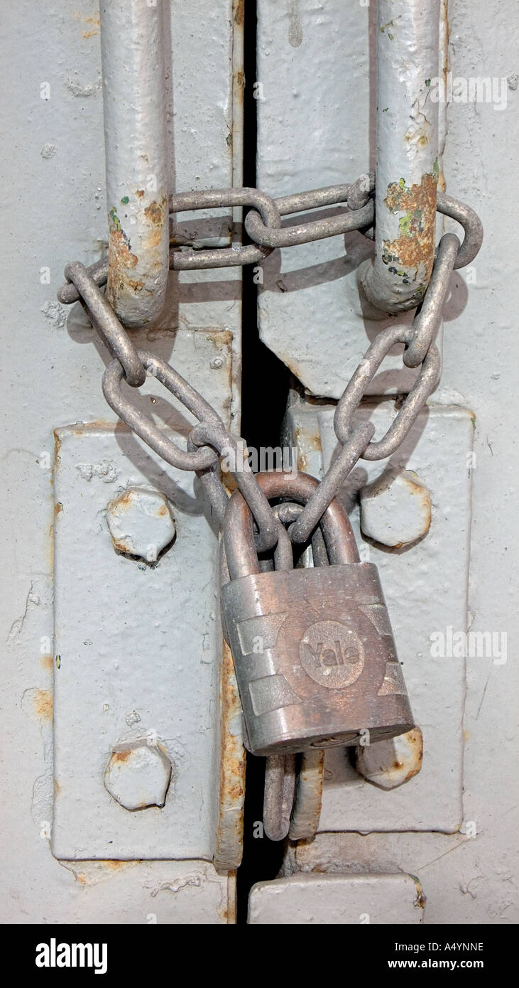 Les poignées d'une porte en acier lourd enchaîné et verrouillé avec un cadenas en Angleterre Banque D'Images