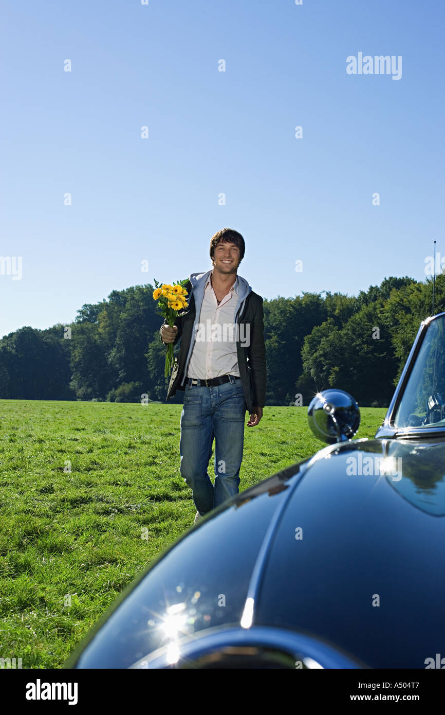 Man holding Flowers in field Banque D'Images